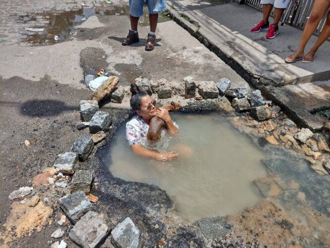 Idosa toma banho em cratera no meio da rua por não ter água da COMPESA em casa